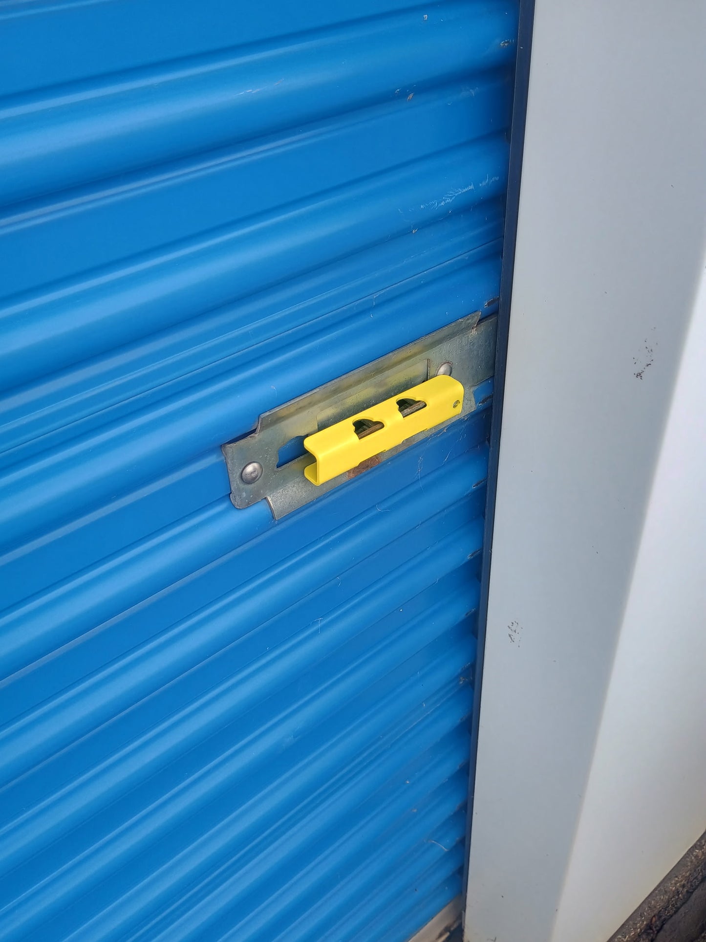 Slide Latch Lock Shield in Powder-coat Yellow installed on storage door